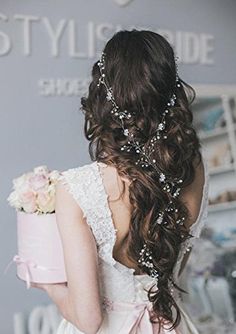 the back of a bride's head with flowers in her hair, holding a pink cake