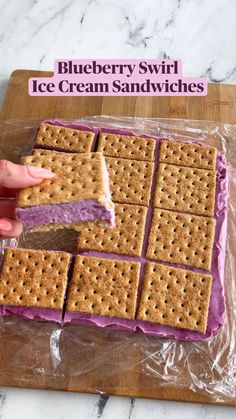 a person is holding a cracker over some ice cream sandwiches