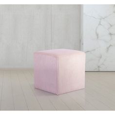 a pink stool sitting on top of a hard wood floor next to a white wall