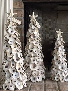 three ceramic christmas trees sitting next to each other in front of a fireplace with seashells on them