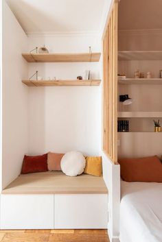 a room with some shelves and pillows on the floor next to a bed in it