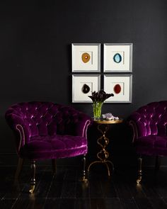 two purple chairs sitting next to each other in front of a wall with pictures on it