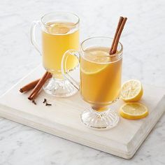 two mugs of tea with cinnamon and lemon on a tray