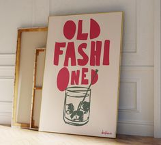 an old fashion poster is on the floor next to a frame with a drink in it