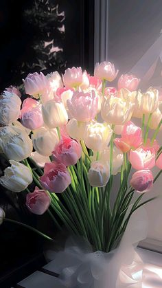 a vase filled with lots of pink and white tulips