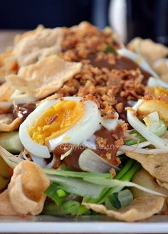 a salad with hard boiled eggs, onions, lettuce and tortilla chips