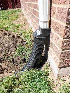 a pipe sticking out of the side of a brick building next to a green lawn