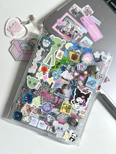 an assortment of stickers and magnets in a clear plastic case next to a laptop