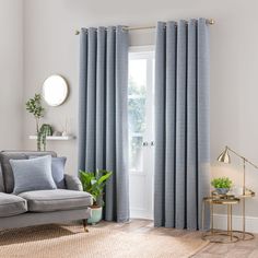 a living room with a couch, chair and window covered in light blue drapes