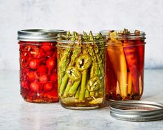 three jars filled with pickled vegetables sitting next to each other