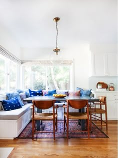 an image of a living room with blue and white pillows on the couches, dining table