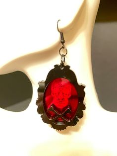 Get ready for Halloween with these eye-catching Sugar Skull and Crossbones Framed Earrings! Crafted from red mirrored acrylic and black acrylic, the laser engraved sugar skull design and laser cut frame with crossbones make for a striking and unique accessory. Show off your gothic style and add an edgy touch to any outfit with these must-have earrings! Each earring is made with 2 layers of 3MM acrylic, but are VERY LIGHT WEIGHT!French hook with silicone stoppers. Earrings are 2" X 1.5" long. *** Gothic Red Jewelry For Halloween, Red Gothic Jewelry For Halloween, Red Novelty Jewelry For Halloween, Nickel-free Red Halloween Jewelry, Red Nickel-free Jewelry For Halloween, Spooky Red Halloween Jewelry, Red Pierced Halloween Earrings, Red Metal Halloween Earrings, Red Pierced Earrings For Halloween