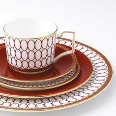 a cup and saucer sitting on top of each other with gold trimmings