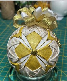 an ornament with gold and white designs on it sitting on a green surface