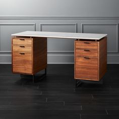 an office desk with two drawers in front of a gray wall and hardwood flooring