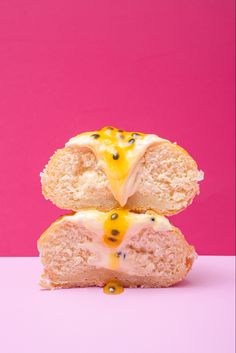 two doughnuts stacked on top of each other in front of a pink background