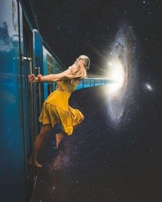 a woman in a yellow dress leaning on a train door and looking at the stars