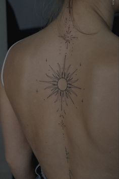 the back of a woman's shoulder with an intricate tattoo design on her left side