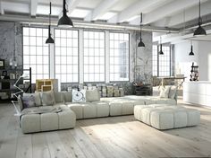 a woman standing next to a large white couch in a living room with lots of windows