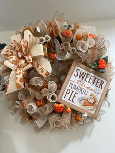 a wreath made out of newspaper strips and pumpkins is hanging on the wall next to a sign that says sweeter pumpkin pie