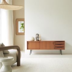 a living room with a white rug and wooden cabinet in the corner next to a window