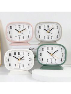 four clocks sitting on top of a white table