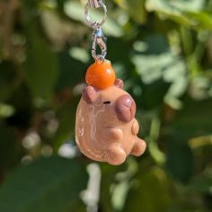 a toy pig hanging from a chain with an orange ball on it's head