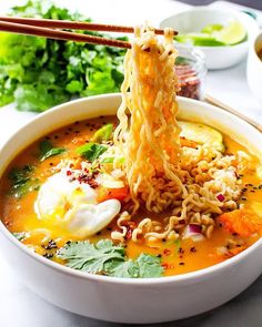 a bowl of ramen with chopsticks sticking out of it and vegetables on the side