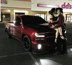 a couple kissing in front of a red truck