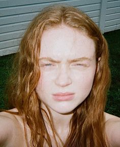 a woman with long red hair is looking at the camera while she has her eyes closed