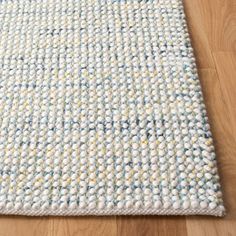 a white and blue rug on top of a wooden floor next to a wood floor