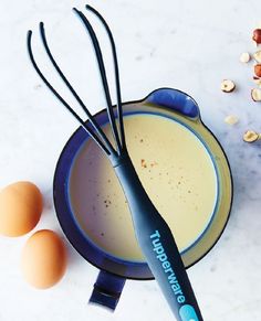 an egg is sitting in a bowl next to eggs and whisk tongs