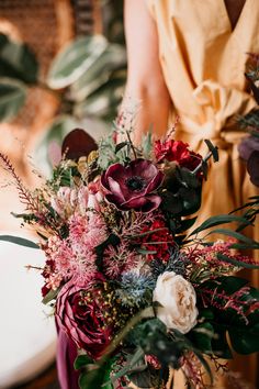 a woman in a yellow dress is holding a bouquet with red, white and purple flowers