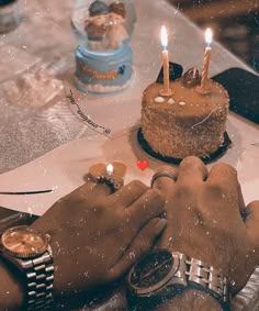 two people holding hands over a cake with candles on it