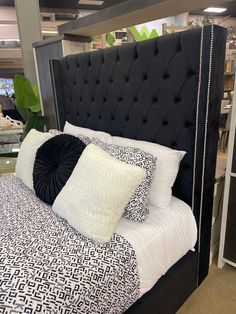 a bed with black headboard and white pillows on display at a furniture showroom