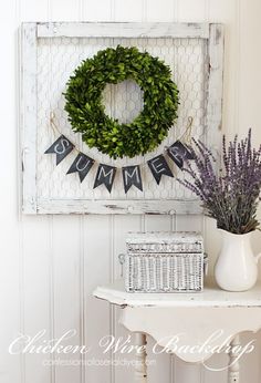 a sign that says welcome with a wreath on it and some flowers in a vase