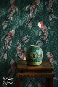 a vase sitting on top of a wooden table in front of a wall with fish