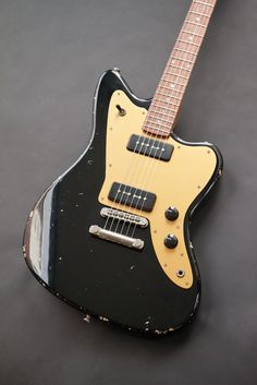 an old black and yellow guitar sitting on top of a gray surface with its neck missing