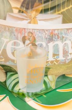 a shot glass sitting on top of a table next to a plate with an image of a man and woman