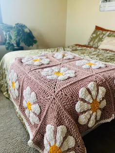 a crocheted bedspread with white and yellow flowers on it in a bedroom