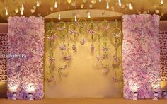 an image of a wedding stage setting with flowers on the wall and chandeliers hanging from the ceiling