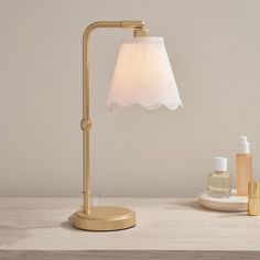 a table lamp with a white shade on it next to some skin care products and an empty bottle