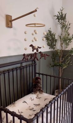 a baby crib with a stuffed animal in it next to a potted tree