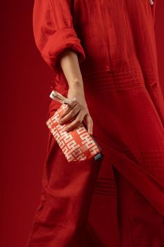 a woman in a red dress holding an orange and white bag