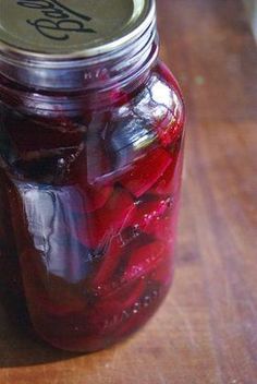 a jar filled with pickles sitting on top of a wooden table