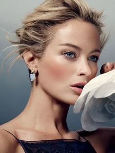 a beautiful woman with blue eyes holding a white rose in her hand and looking at the camera