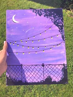 someone is holding up a purple canvas with string lights and the moon in the sky