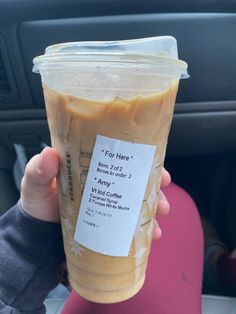 a person holding up a plastic cup filled with coffee