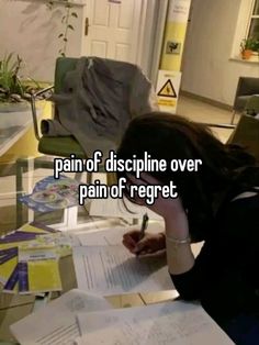 a woman sitting at a table with papers and pen in her hand, writing on paper