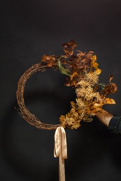 a person holding a bunch of dried flowers in front of a black background with leaves